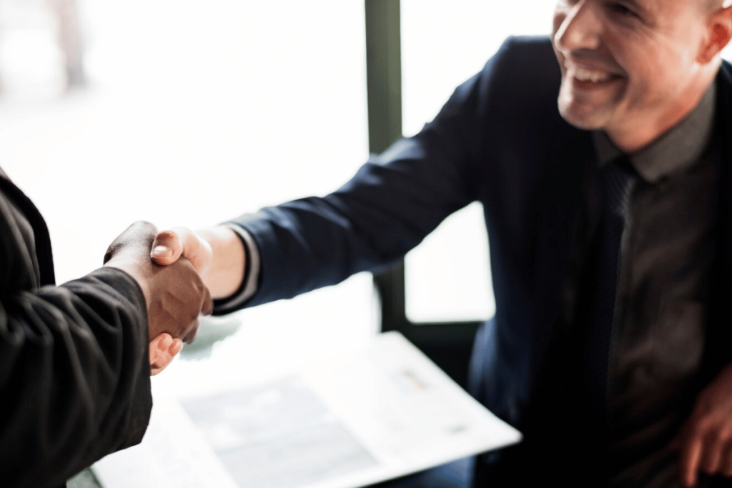 Two executives shaking hands in an office.
